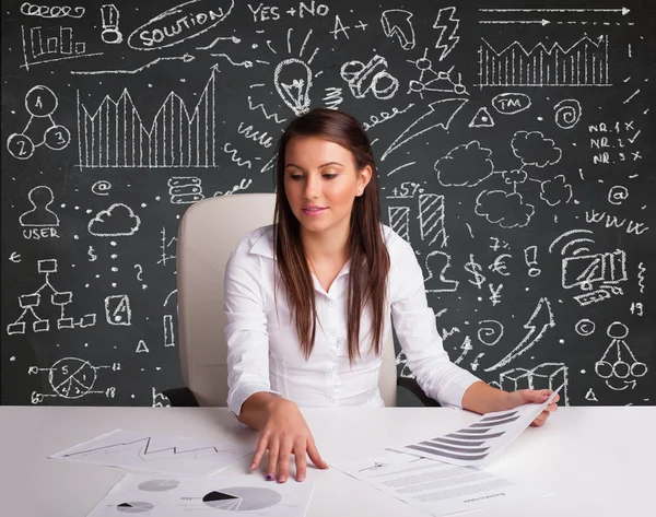 Bizneswoman siedzi przy biurku z schematem biznesowym i ikonami — Zdjęcie stockowe