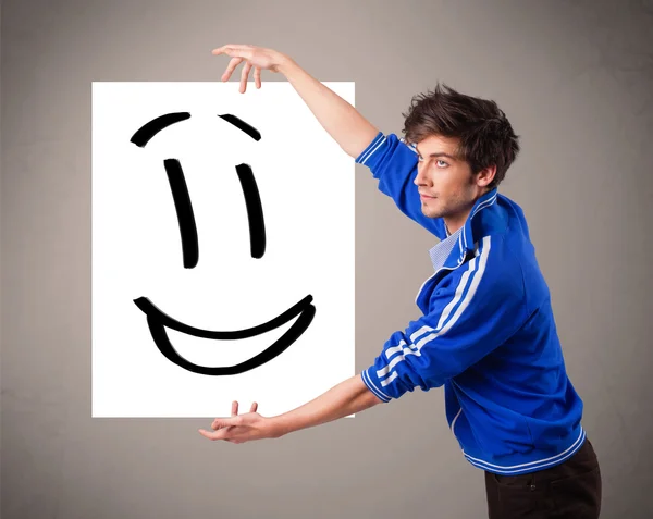 Jovem menino segurando sorridente rosto desenho — Fotografia de Stock