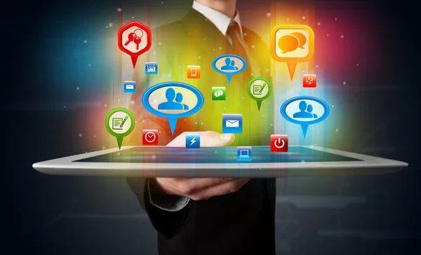 Empresário apresentando tablet moderno com sinais sociais coloridos — Fotografia de Stock
