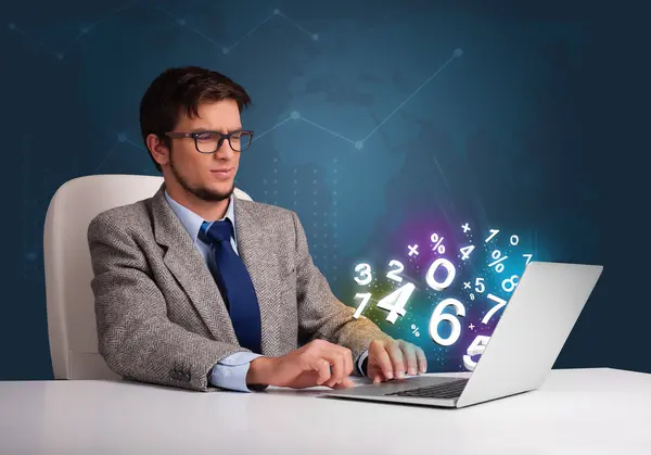 Hombre guapo sentado en el escritorio y escribiendo en el ordenador portátil con número 3d — Foto de Stock