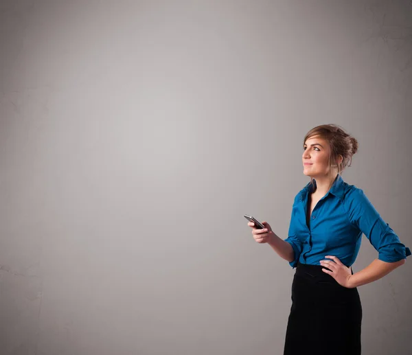 Young lady standing and holding a phone with copy space — Stock Photo, Image