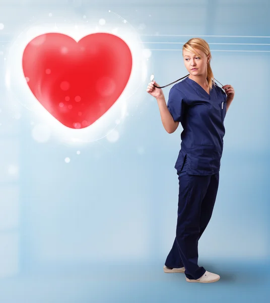 Enfermeira jovem curando um coração vermelho — Fotografia de Stock