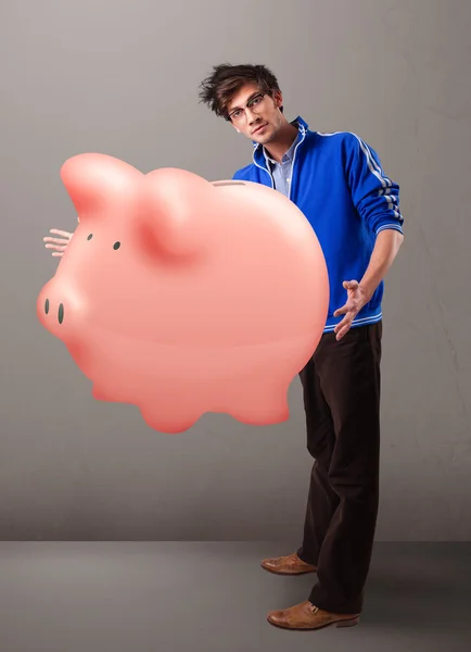 Bonito homem segurando um enorme banco de poupança porquinho — Fotografia de Stock