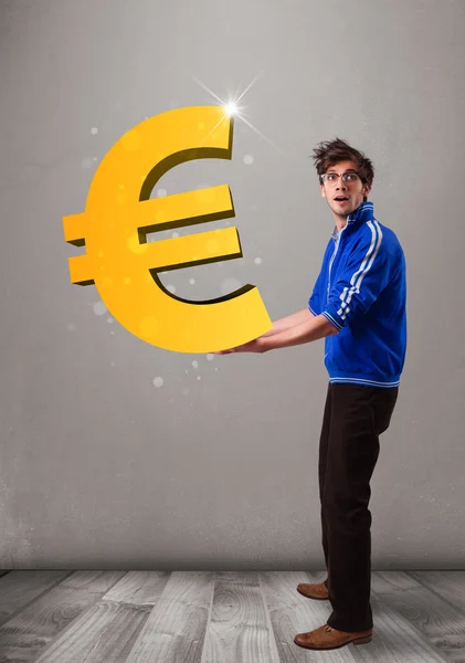 Good-looking boy holding a big 3d gold euro sign — Stock Photo, Image