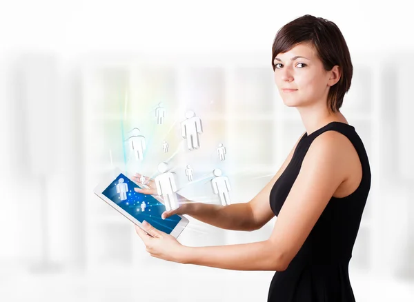 Молодая женщина смотрит на современный планшет с социальными иконами — стоковое фото