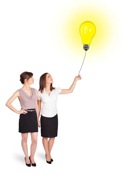 Mulheres felizes segurando um balão de lâmpada — Fotografia de Stock