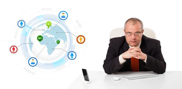 Businessman sitting at desk with a globe and social icons Stock Picture
