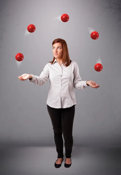 Ung flicka står och jonglerar med röda bollar — Stockfoto