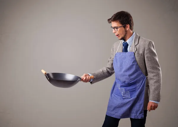 Молодой человек держит черную сковородку — стоковое фото