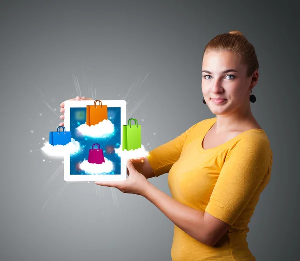 Женщина держит современный планшет с красочными мешками для покупок на облаке — стоковое фото