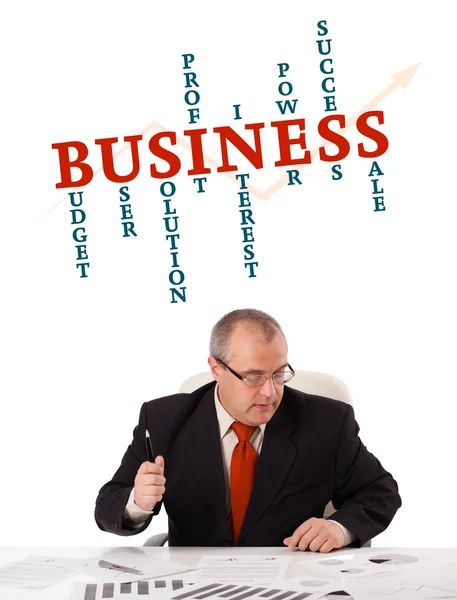 Affärsman som sitter vid skrivbord med word cloud — Stockfoto