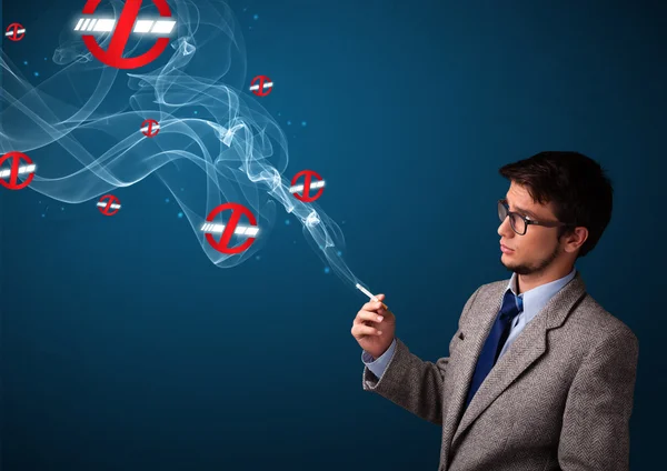 Attractive man smoking dangerous cigarette with no smoking signs — Stock Photo, Image