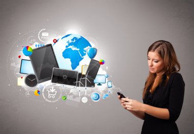 Genç bir kadın ayakta ve telefonunda geziniyor.