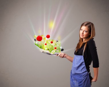 Genç bir kadın taze sebze pişiriyor.