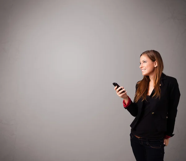 Joven dama de pie y sosteniendo un teléfono con espacio para copiar — Foto de Stock