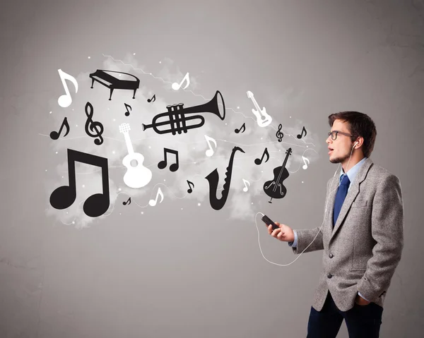 Attraktive unge mand synger og lytter til musik med musikalsk - Stock-foto
