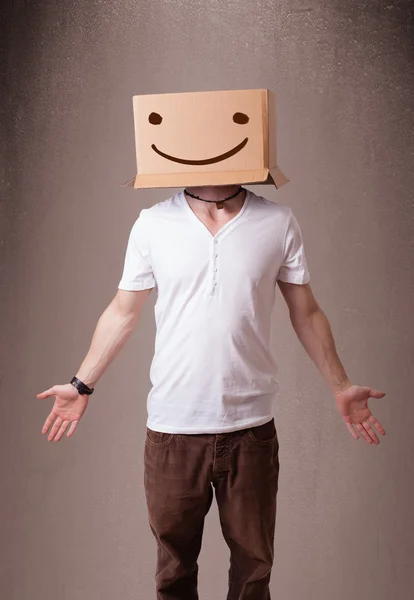 Jeune homme gesticulant avec une boîte en carton sur la tête avec un sourire — Photo