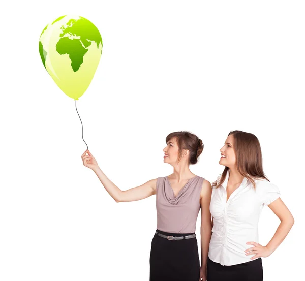Glada damer som håller en grön glob ballong — Stockfoto