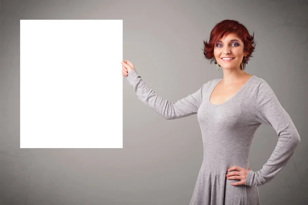 Mladá žena představující bílý papír kopírovat prostor — Stock fotografie