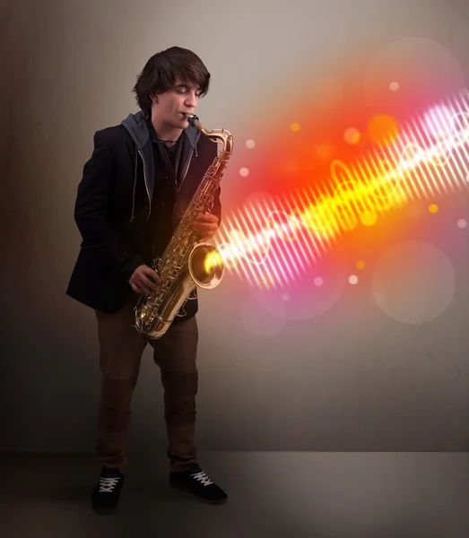 Young man playing on saxophone with colorful sound waves — Stock Photo, Image