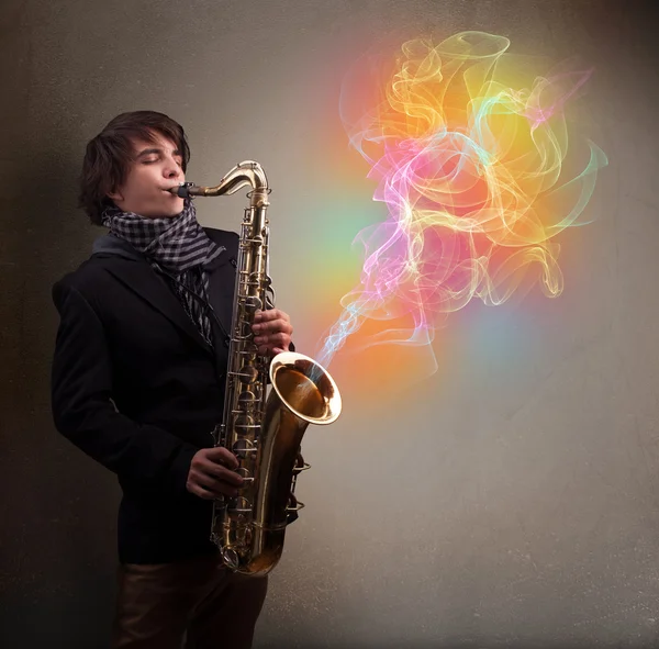 Atraktivní hudebník hrající na saxofon s barevnými abstrakt — Stock fotografie