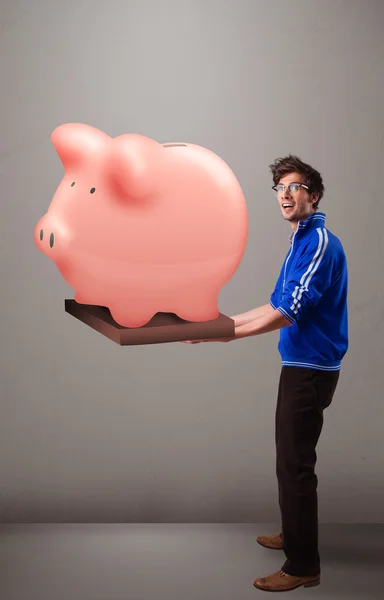 Handsome man holding a huge savings piggy bank — Stock Photo, Image