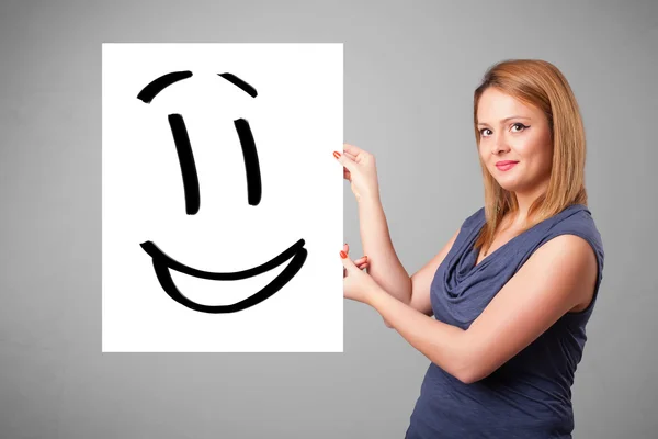 Young woman holding smiley face drawing — Stock Photo, Image