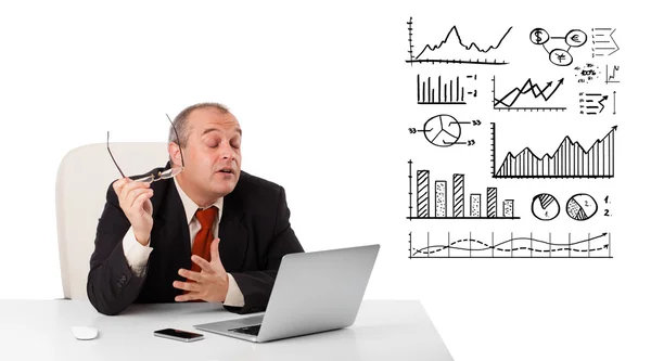 Affärsman som sitter vid skrivbord med diagram och laptop — Stockfoto