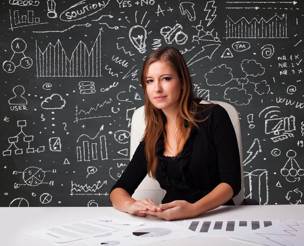 Businesswoman sitting at desk with business scheme and icons — Stock Photo, Image