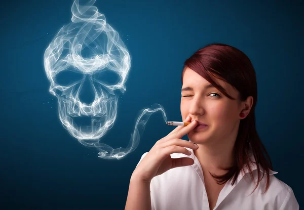 Young woman smoking dangerous cigarette with toxic skull smoke — Stock Photo, Image