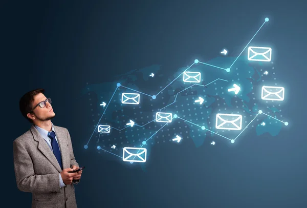 Young man holding a phone with arrows and message icons — Stock Photo, Image