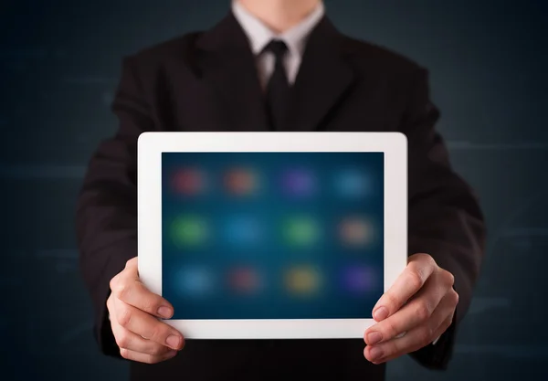 Podnikatel drží bílou moderní tabletu s rozmazanými aplikacemi — Stock fotografie