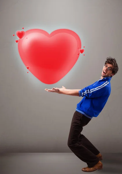 Jovem homem segurando adorável 3d coração vermelho — Fotografia de Stock