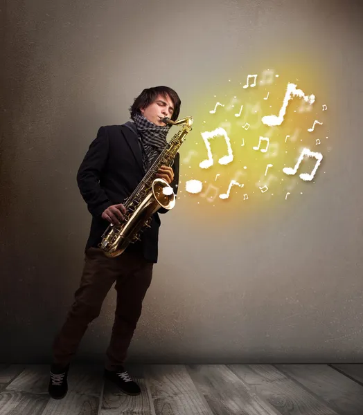 Beau musicien jouant sur saxophone avec des notes musicales — Photo