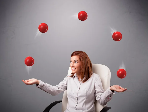 Giovane ragazza seduta e giocoleria con le palle rosse — Foto Stock