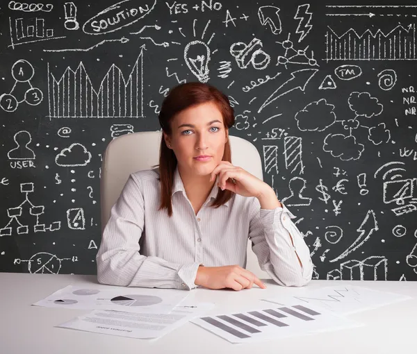 Businesswoman sitting at desk with business scheme and icons — Stock Photo, Image