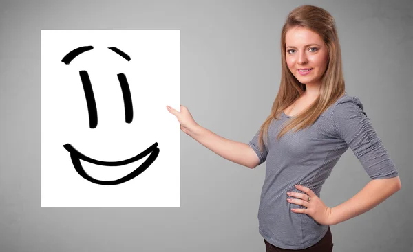 Jovem mulher segurando sorridente desenho rosto — Fotografia de Stock