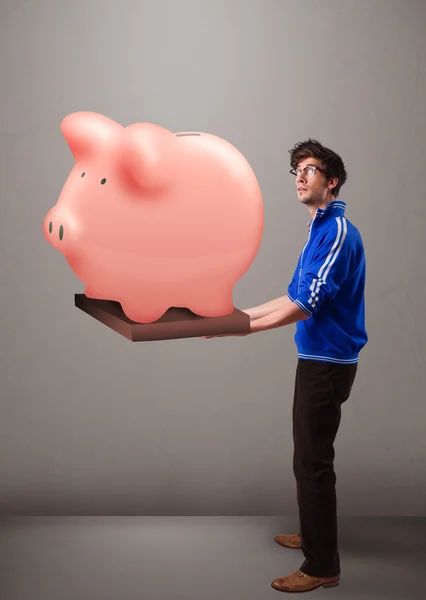 Bonito homem segurando um enorme banco de poupança porquinho — Fotografia de Stock