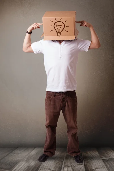 Genç adam ile bir karton kutu ile light kafasına el hareketi — Stok fotoğraf