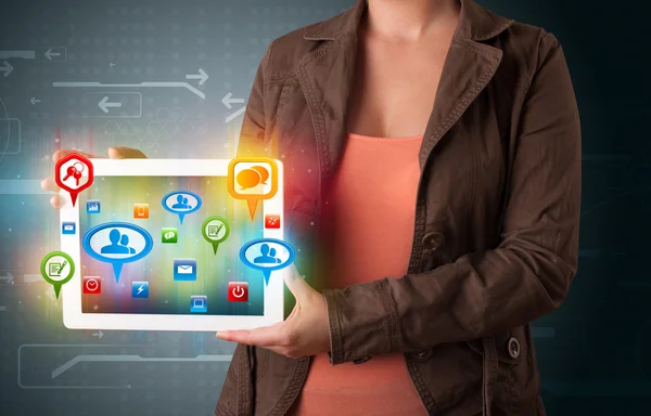 Girl presenting a tablet with colorful social icons and signs — Stock Photo, Image