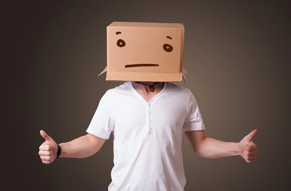 Jovem gesticulando com uma caixa de papelão na cabeça com straig — Fotografia de Stock