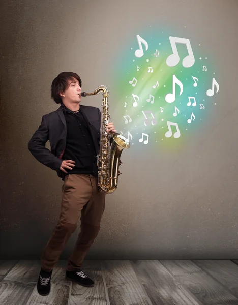 Jeune musicien jouant sur saxophone tandis que les notes de musique explosent — Photo