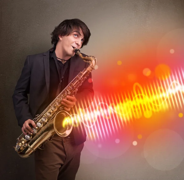 Joven tocando el saxofón con ondas sonoras coloridas —  Fotos de Stock