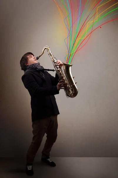 Atraktivní hudebník hrající na saxofon, zatímco barevné abstraktní — Stock fotografie