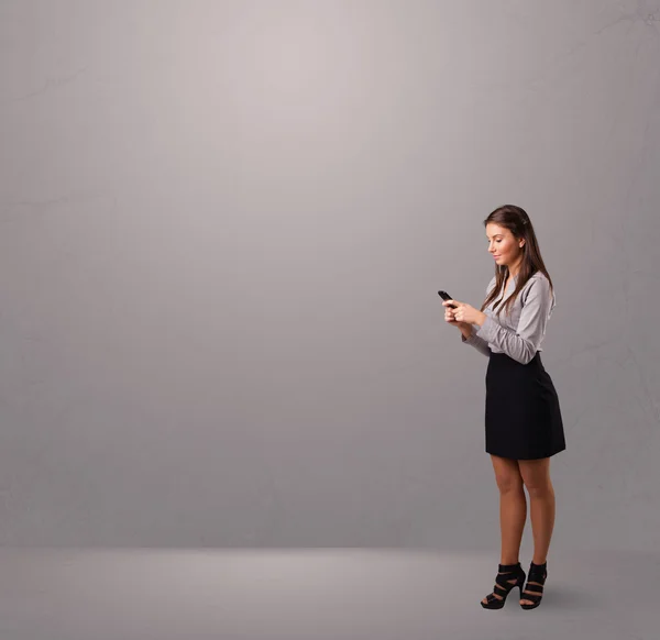 Young lady standing and holding a phone with copy space — Stock Photo, Image