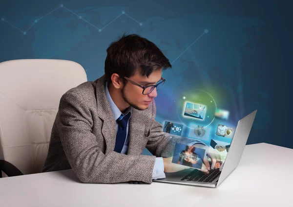 Young man sitting at desk and watching his photo gallery on lapt — Stock Photo, Image