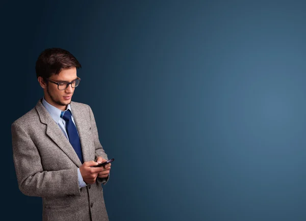 Junger Mann steht und tippt auf ihrem Handy mit Kopierplatz — Stockfoto