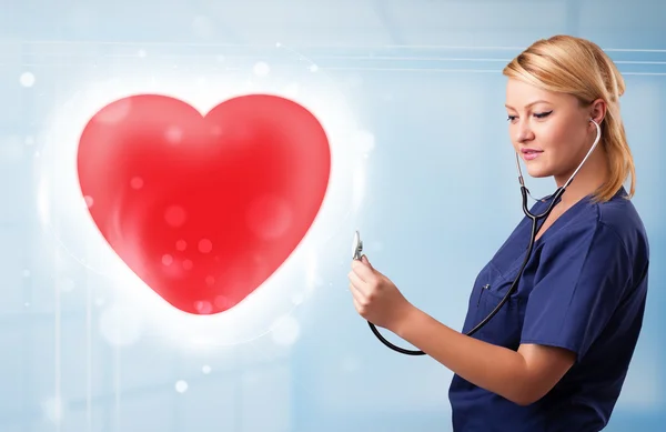 Enfermera joven curando un corazón rojo — Foto de Stock