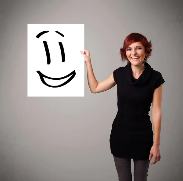 Young woman holding smiley face drawing — Stock Photo, Image