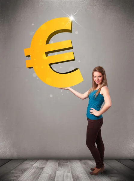 Beautiful girl holding a big 3d gold euro sign — Stock Photo, Image